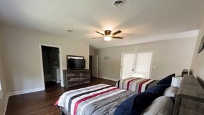 Ein Schlafzimmer mit Bett, Deckenventilator, Kommode und Fernseher.