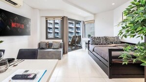 Una sala de estar moderna con televisor, sofá y comedor con mesa y sillas.