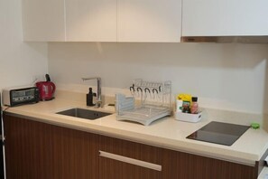 A kitchen with a double sink, a kettle, a toaster, a dish rack, and a spice rack. - Studio for 5 at Tambuli Residences Garden View by Dominik Studio with Pool & Balcony in Mactan (Lapu-Lapu City)