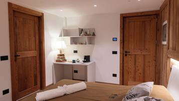 A bedroom with a bed, a desk, and two wooden doors.