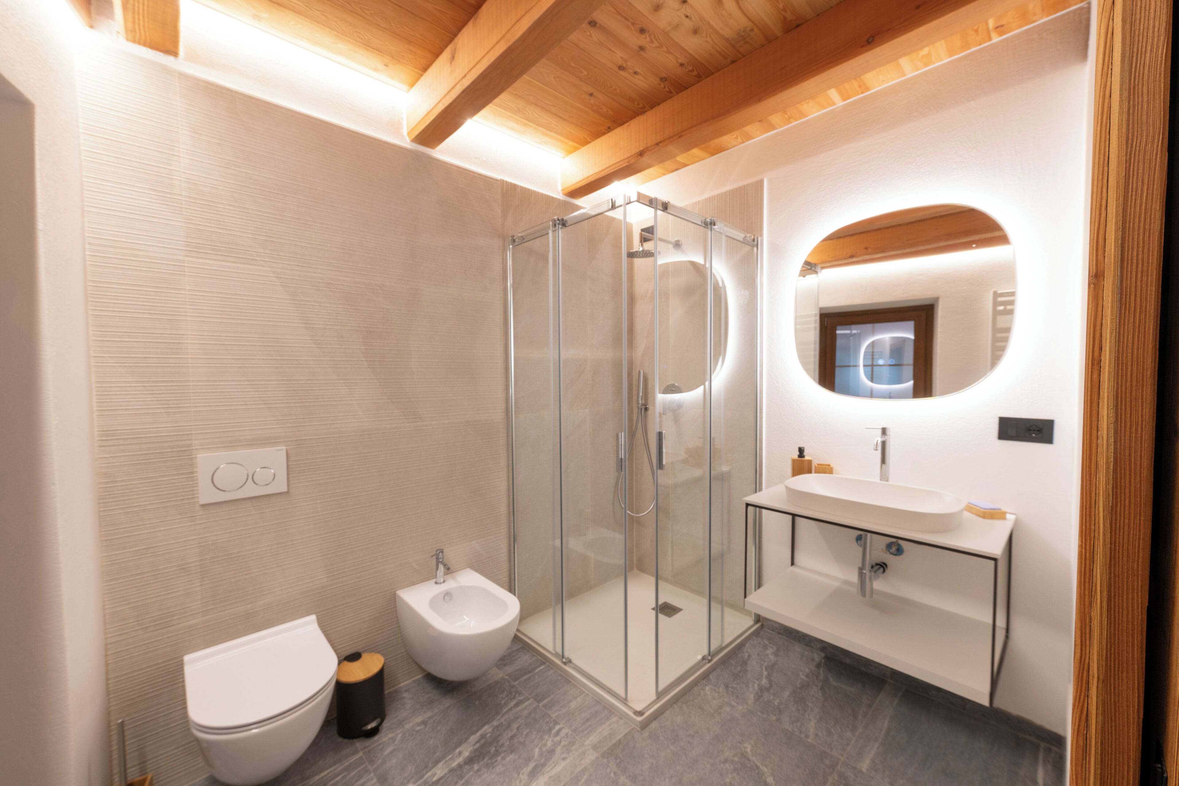 A modern bathroom with a glass-enclosed shower, a bidet, a sink, and a mirror.