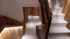Una escalera de madera con escalones blancos y barandal de madera.