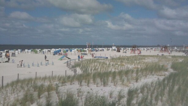 Una playa con tiendas de campaña y gente.