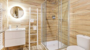 Un baño moderno con diseño de pared de madera, una ducha con cerramiento de vidrio, un lavabo blanco con espejo y un inodoro.