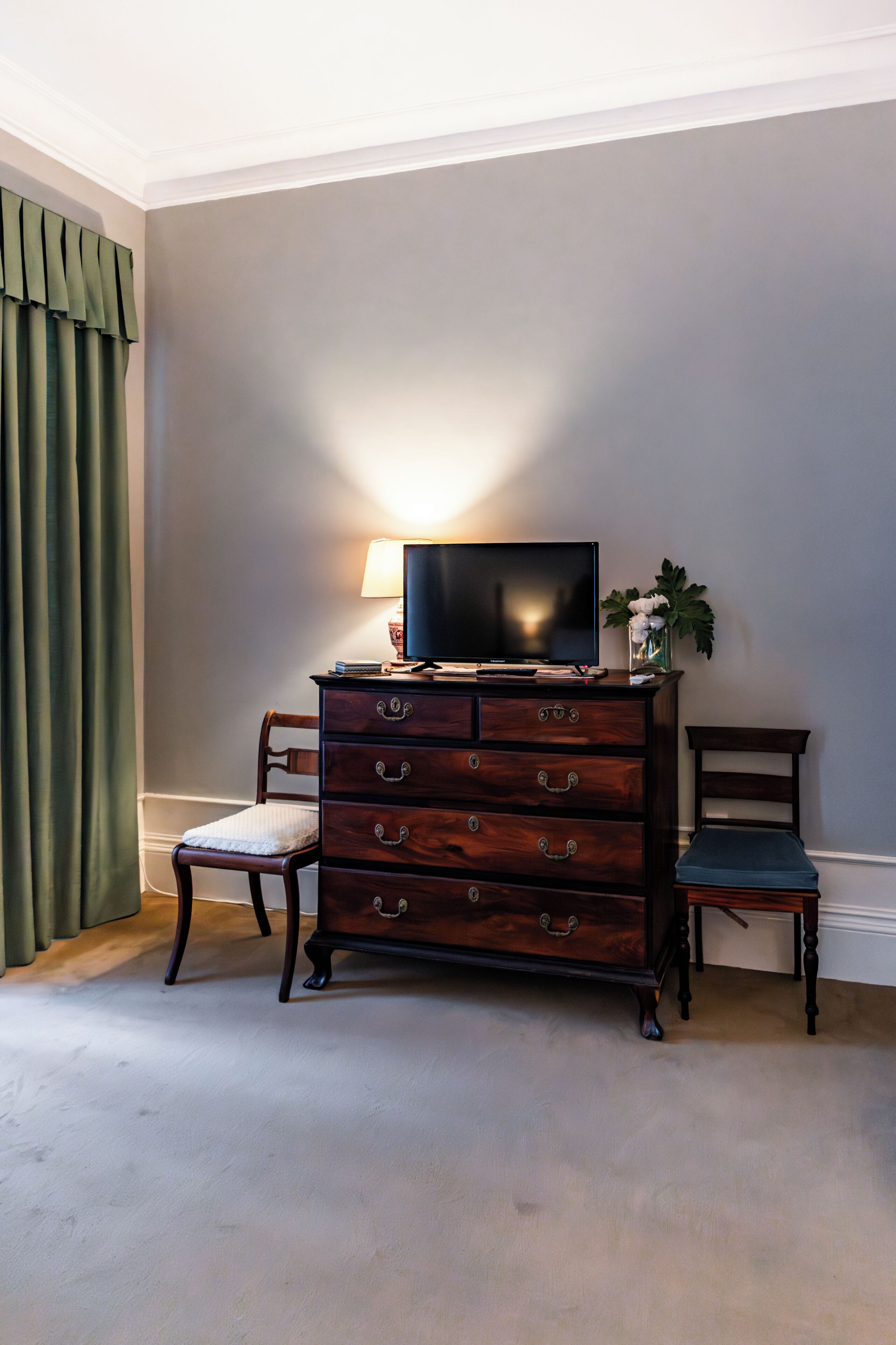 Ein Zimmer mit einem Holzkapfen, einem Fernseher, einem Stuhl und einer Lampe.