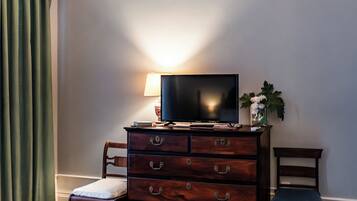 Una habitación con un aparador de madera, televisor, una silla y una lámpara.