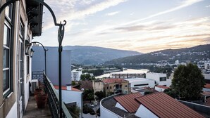 A balcony with potted plants, a view of a river, and buildings in the background. - Douro D'heart - Casa Familiar no Centro da Régua (Peso da Régua)