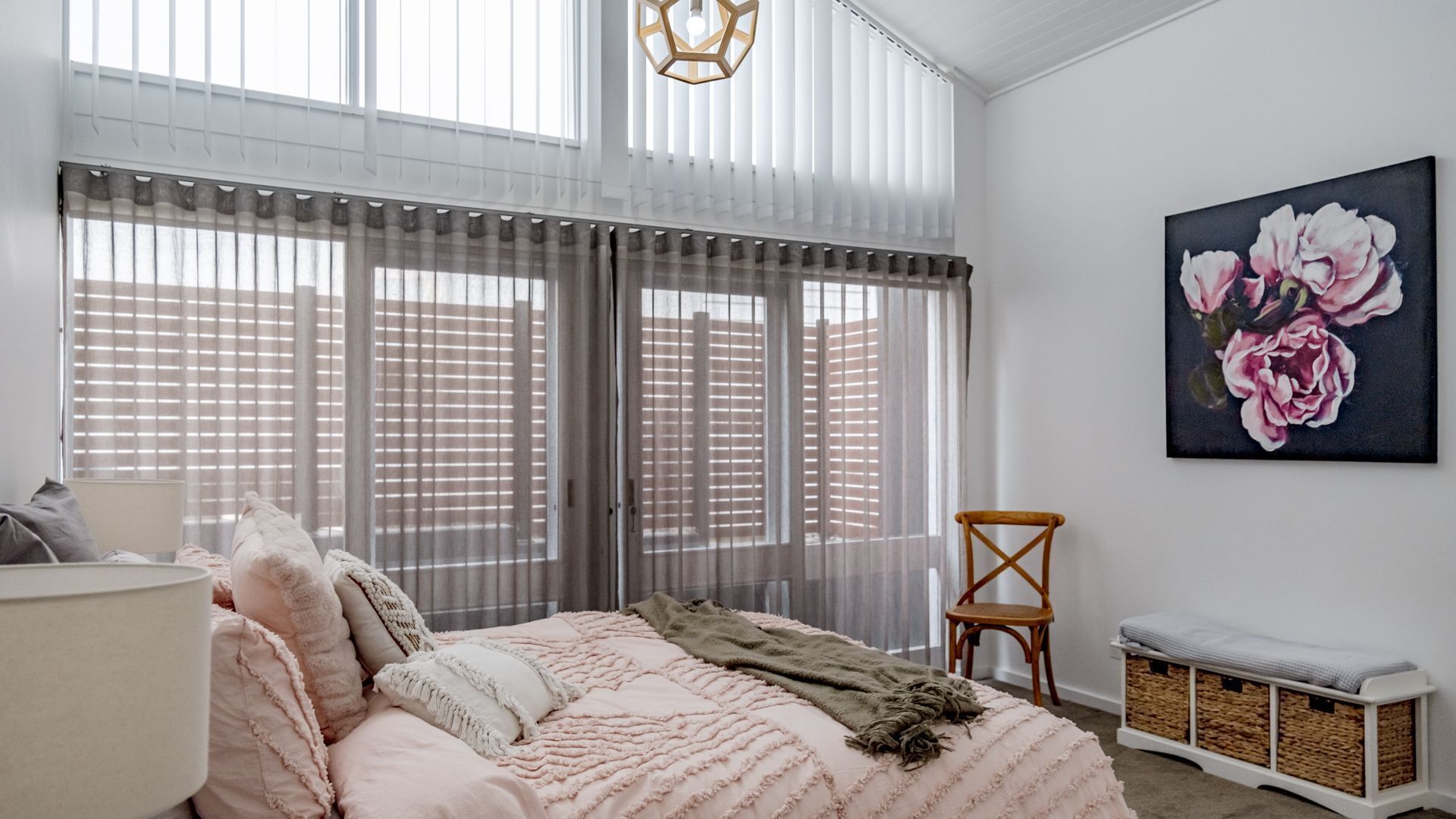 Une chambre à coucher avec un lit, une chaise, un tableau et une fenêtre avec des stores.