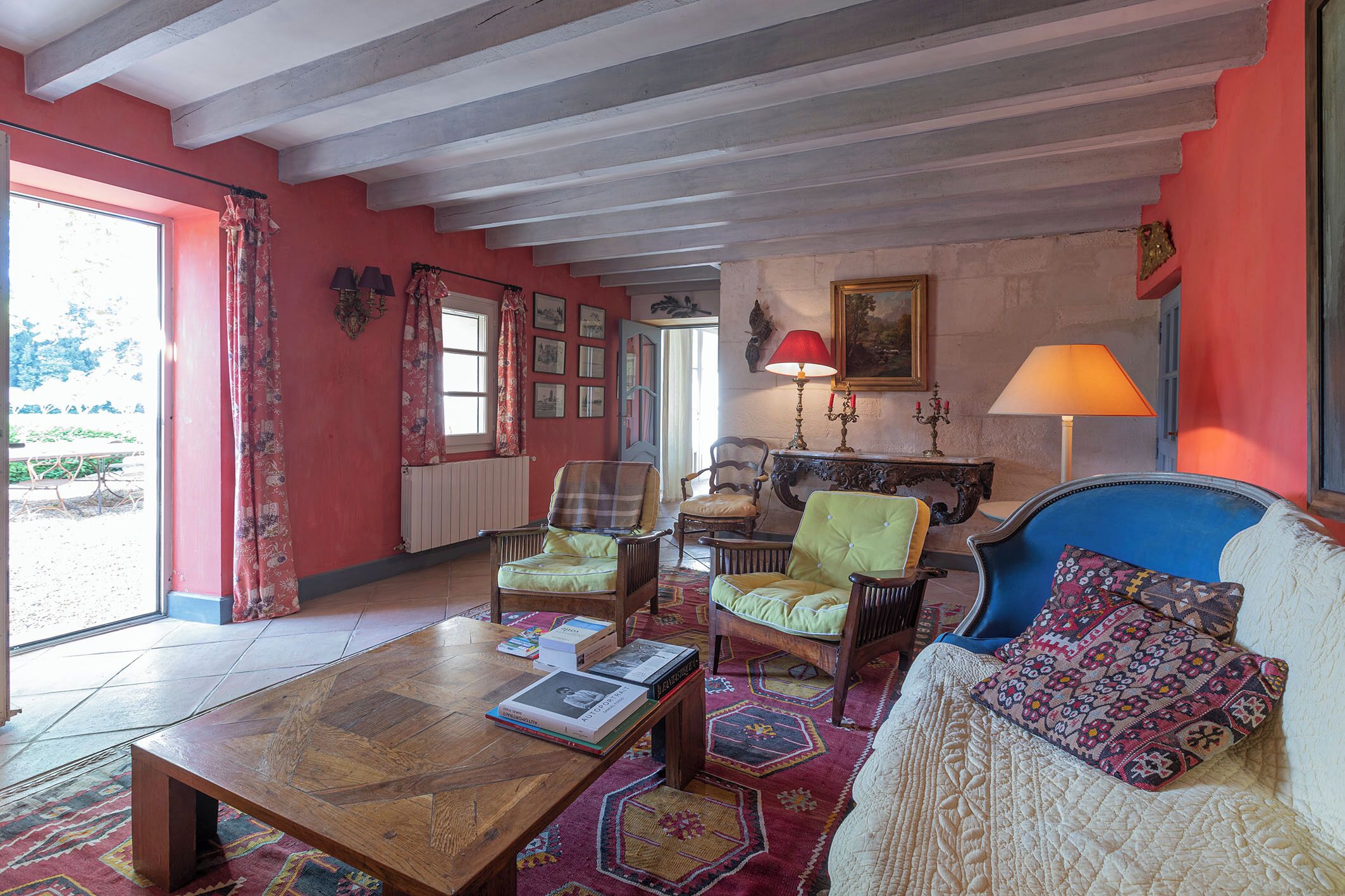 A room with a wooden coffee table, two armchairs, a sofa, and a patterned rug.