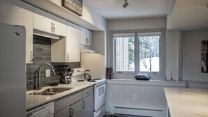 A modern kitchen with a large window, white cabinetry, and a built-in stove.