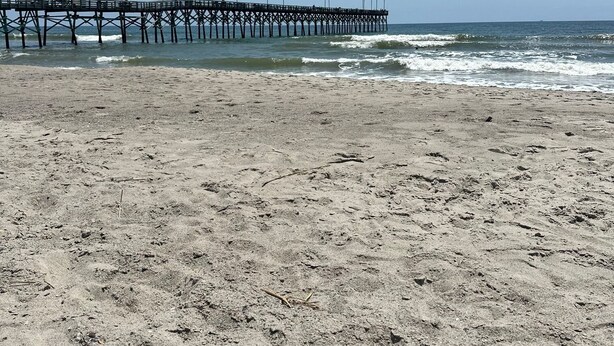 Ein Strand mit einem Steg, der sich ins Meer erstreckt.