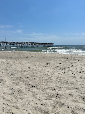 Una spiaggia con un molo che si protende verso l'oceano.