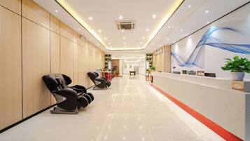 A hotel lobby with a reception desk, massage chairs, and a clean, modern design.