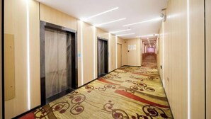 Um corredor de hotel com carpete, portas e um longo caminho que leva a um quarto.