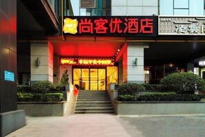 A hotel entrance with a red-lit sign, a staircase, and a well-maintained garden area. - Shankee Hotel (Zhengzhou East High-Speed Rail Station) (Zhengzhou)