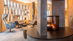 A cozy lounge area with a stone fireplace, comfortable seating, and a decorative wall. - Modern Holiday Apartment With Balcony in Fugen (Fuegen)