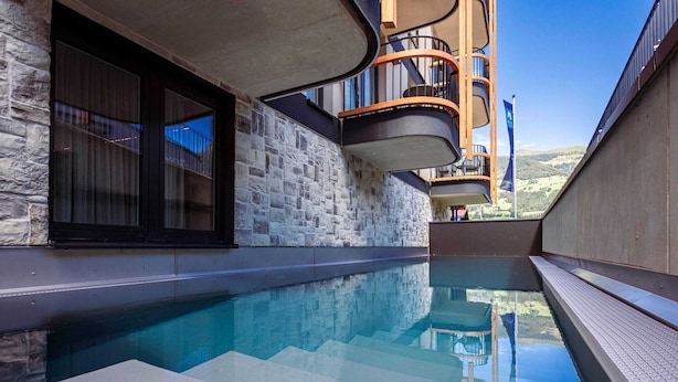 A modern pool area with a stone wall and a curved balcony. - Modern Holiday Apartment With Balcony in Fugen (Fuegen)