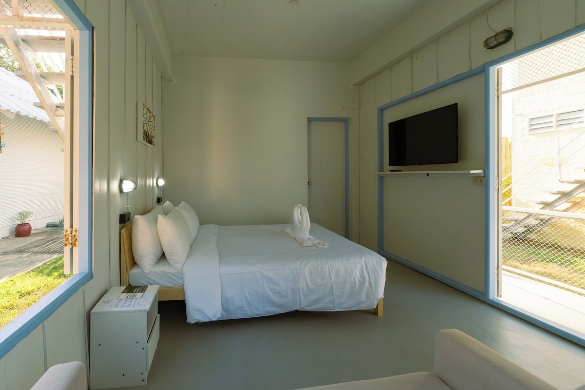 A bedroom with a bed, bedside table, and a TV mounted on the wall.