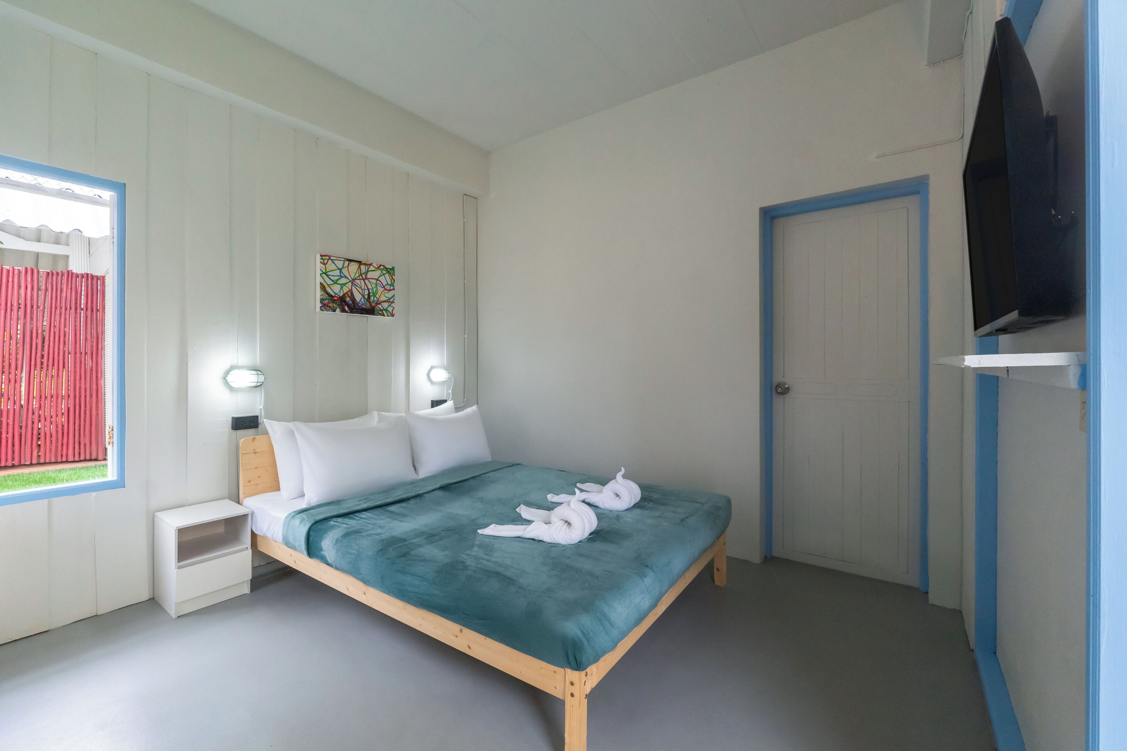 A bedroom with a bed, bedside tables, a TV, and a door.