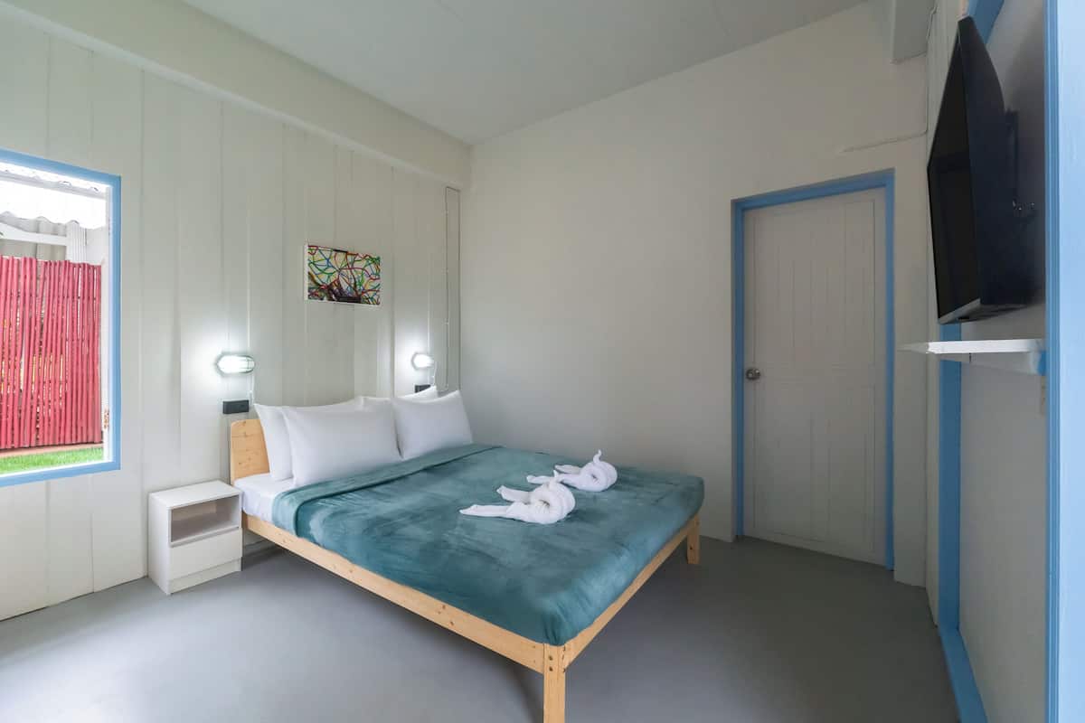 A bedroom with a bed, bedside tables, a TV, and a door.
