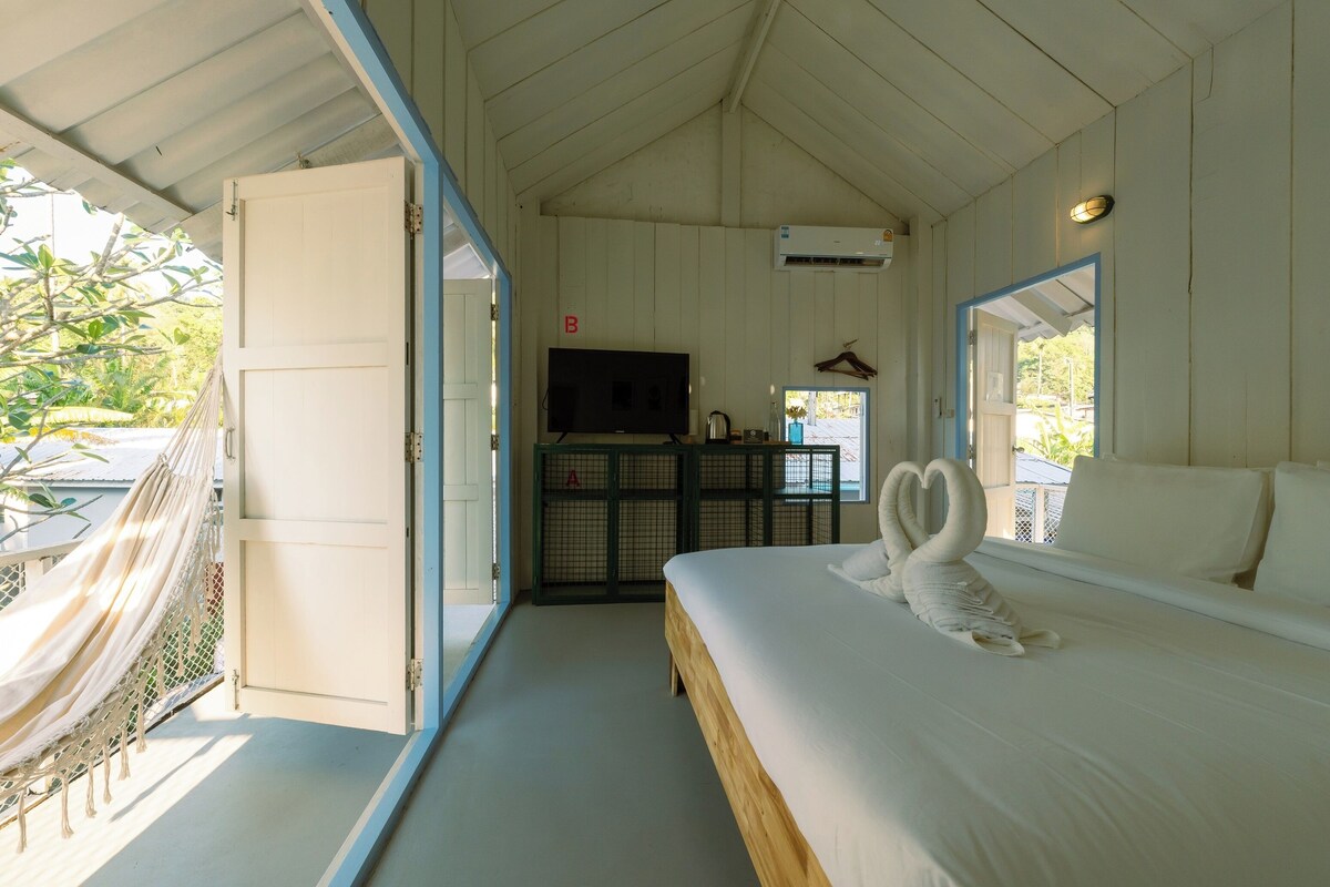 A bedroom with a bed, a TV, and a hammock.