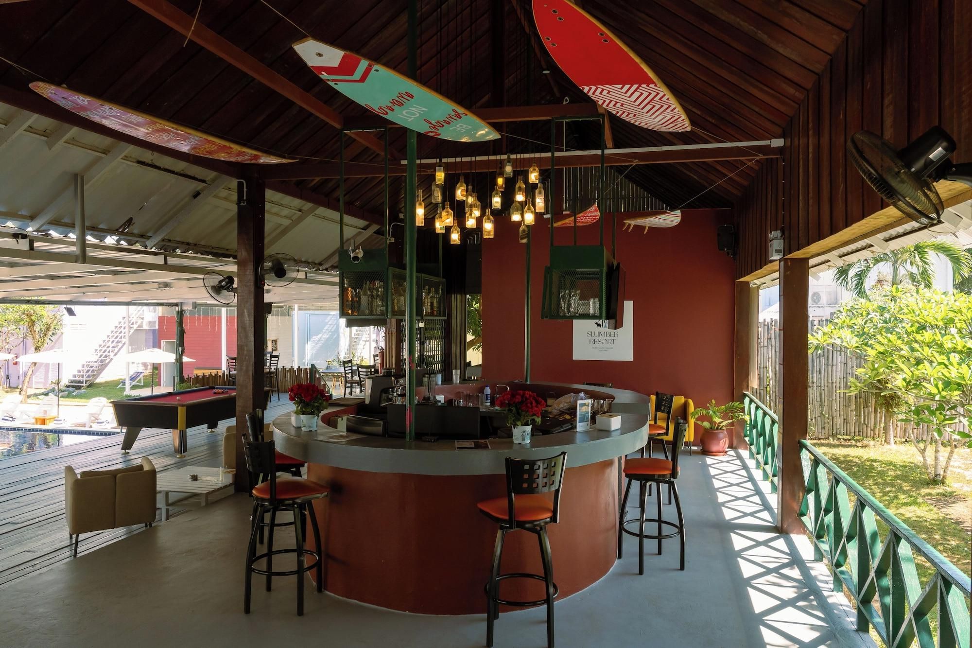 Uma área de bar com balcão, banquetas e luminárias penduradas.