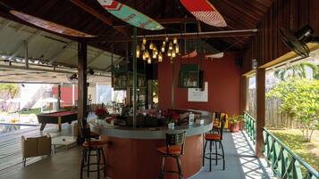 Uma área de bar com balcão, banquetas e luminárias penduradas.