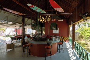 A bar area with a counter, stools, and hanging lights. - Slumber Resort Koh Chang (Ko Chang)