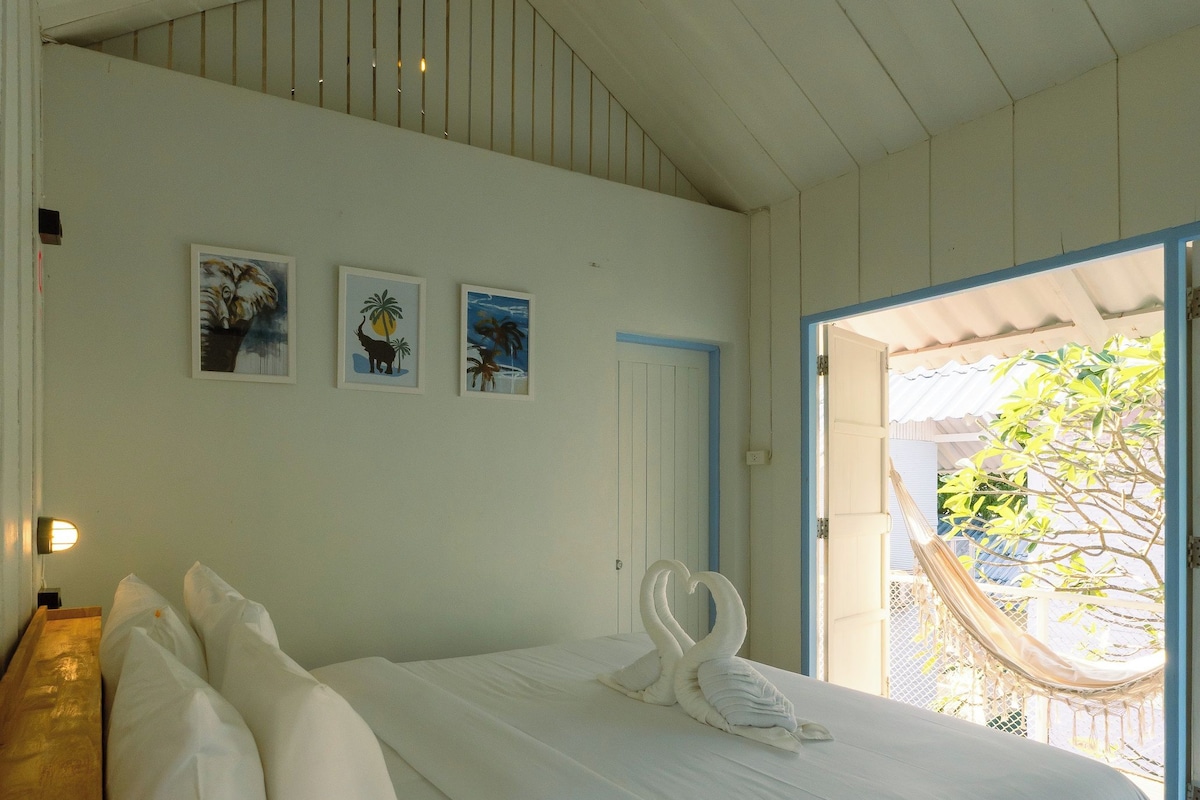 A bedroom with a wooden bed, white bedding, and two wall-mounted pictures.