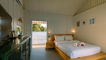 Quarto com cama, uma mesinha com chaleira, janela e porta que dá para o exterior.