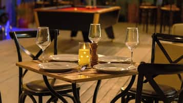 A dining table set for two with chairs, a candle, and a salt shaker.