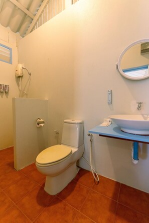 A bathroom with a toilet, a sink, a mirror, and a shower area. - Slumber Resort Koh Chang (Ko Chang)