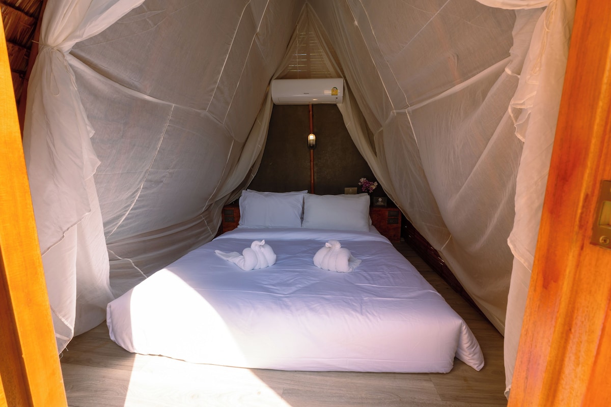 A bed with a canopy, a bedside table, and a wall-mounted air conditioner.