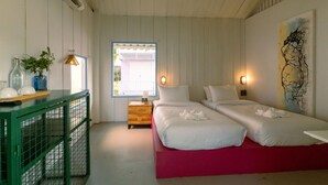 A room with two beds, a wooden nightstand, a green table with a plant, and a window with a view. - Slumber Resort Koh Chang (Ko Chang)