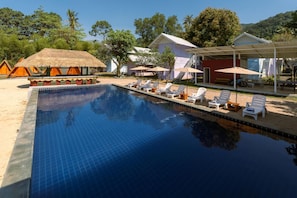 A swimming pool with lounge chairs, a thatched-roof structure, and a covered seating area. - Slumber Resort Koh Chang (Ko Chang)