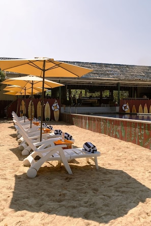 A beachside lounge area with sun loungers, umbrellas, and surfboards. - Slumber Resort Koh Chang (Ko Chang)