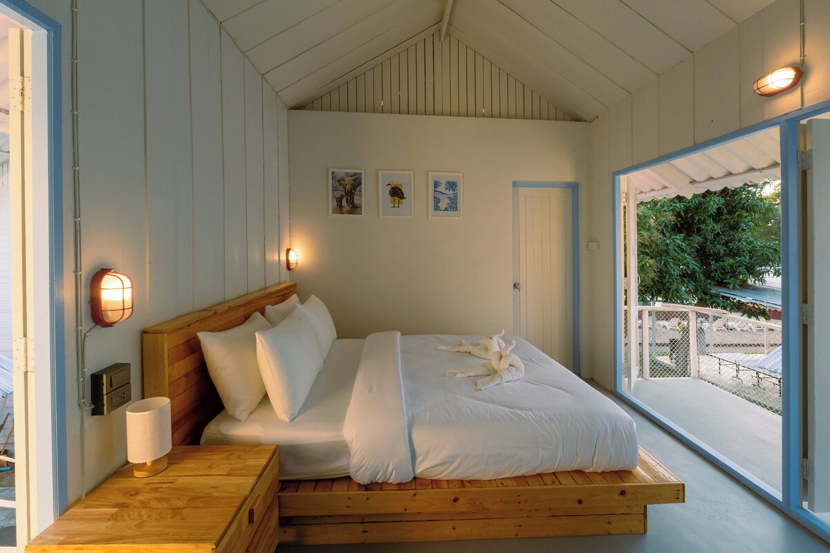 A bedroom with a wooden bed, white bedding, and two wall-mounted lights.