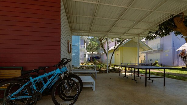 A covered outdoor area with a table and chairs, a blue bicycle, and a building in the background. - Slumber Resort Koh Chang (Ko Chang)
