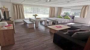A modern living room with a sofa, a dining table, and a bed. - Lakeside Escape With Garden Fun (Goldberg)