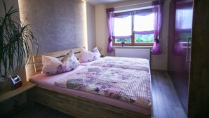 Een slaapkamer met een houten bed, een kamerplant en een raam met gordijnen.