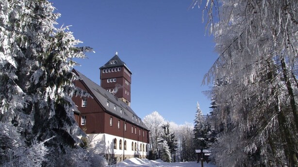 Een besneeuwd landschap met een historisch gebouw, voorzien van een toren en gebogen ramen.