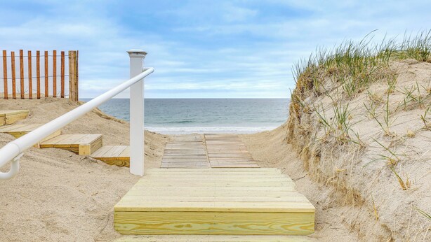 A wooden staircase leading to a beach with a wooden fence on one side and a white railing on the other. - Beachfront Salisbury Retreat w/ Grill (Salisbury)