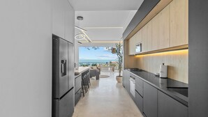 Une cuisine moderne avec vue sur la mer, au design épuré, et un espace repas avec des sièges en plein air.