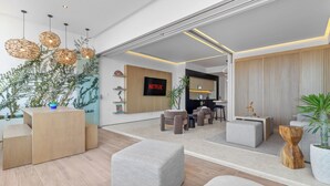 Un salon moderne avec un téléviseur, des sièges et un mur végétal.