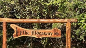A wooden sign with the text "The Hideaway" mounted on a rustic wooden frame. - Cedar  Gap  Hideaway (Birdseye)