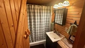 A wooden cabin bathroom with a shower, sink, and mirror. - Cedar  Gap  Hideaway (Birdseye)