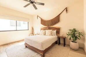 A bedroom with a bed, a ceiling fan, a hammock, a nightstand, a bedside table, and a potted plant. - Jungle Jade Penthouse Private Rooftop Pool Oasis (Tulum)