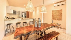 A modern kitchen with a large island, pendant lights, and a woven wall hanging. - Jungle Jade Penthouse Private Rooftop Pool Oasis (Tulum)