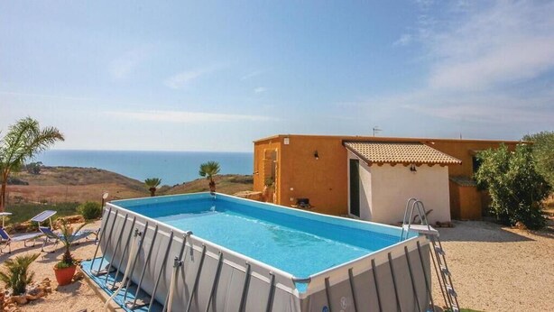 Una piscina con vistas al mar, un edificio pequeño y una escalera.