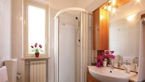 Un baño con inodoro, ducha, lavabo y ventana con flores.